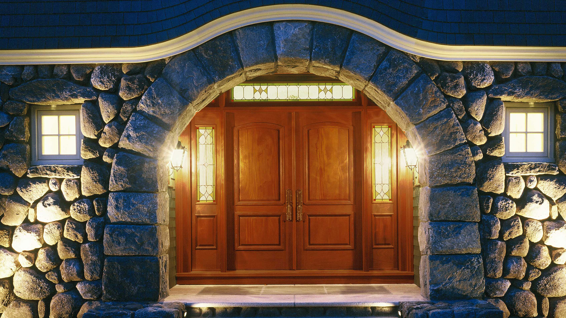 Concord Massachusetts stone arch entry with custom mahogany doors and stained glass sidelights